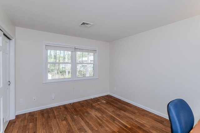 unfurnished bedroom with baseboards, a closet, dark wood-style floors, and visible vents