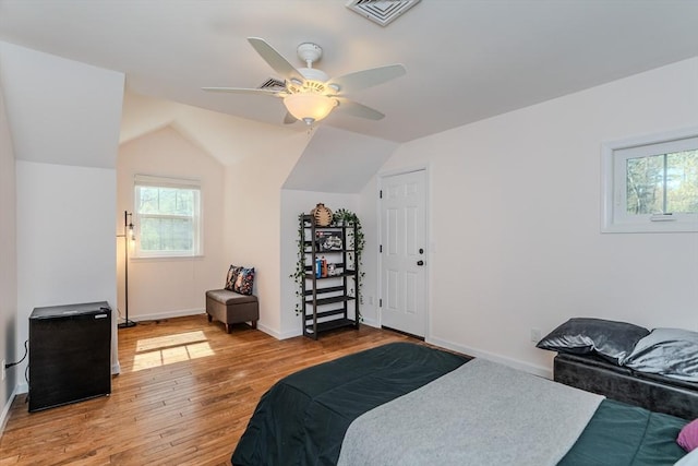 bedroom featuring multiple windows, vaulted ceiling, wood finished floors, and visible vents