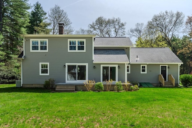 back of house featuring central AC unit, a yard, a chimney, and entry steps