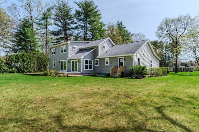 back of property featuring roof with shingles, a chimney, and a yard