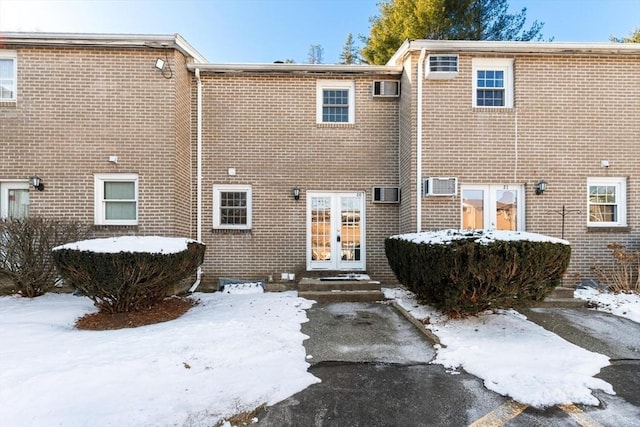 snow covered property with a wall mounted air conditioner