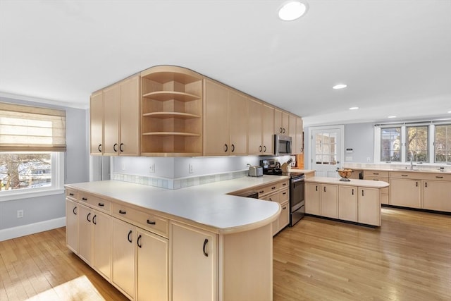 kitchen featuring light brown cabinetry, a center island, light hardwood / wood-style flooring, appliances with stainless steel finishes, and kitchen peninsula