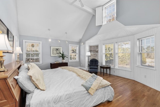 bedroom with hardwood / wood-style flooring, high vaulted ceiling, multiple windows, and beam ceiling