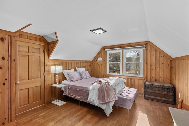 bedroom with hardwood / wood-style flooring, vaulted ceiling, and wood walls