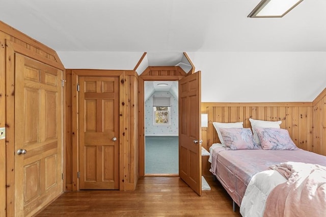 bedroom featuring vaulted ceiling, hardwood / wood-style floors, and wood walls