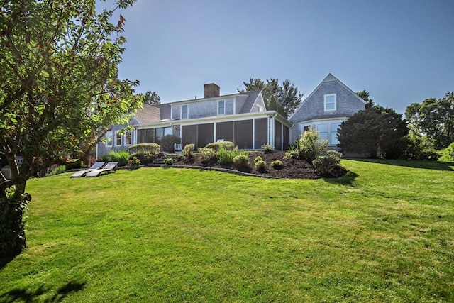 rear view of house with a sunroom and a yard