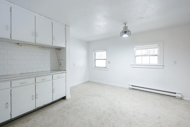 kitchen with hanging light fixtures, white cabinets, light carpet, decorative backsplash, and a baseboard radiator