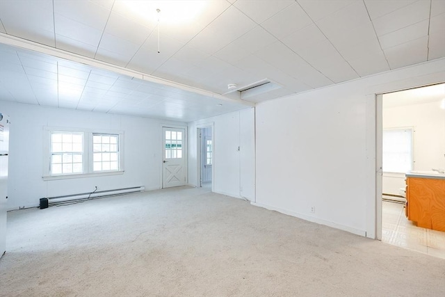 spare room with baseboard heating, sink, and light carpet