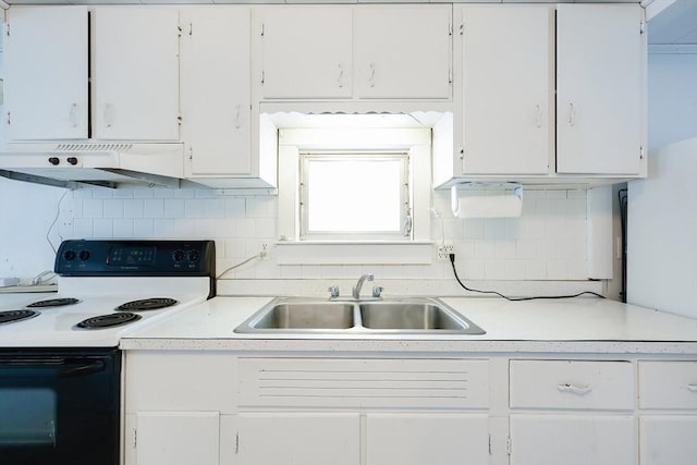 kitchen with tasteful backsplash, white cabinets, sink, and electric range