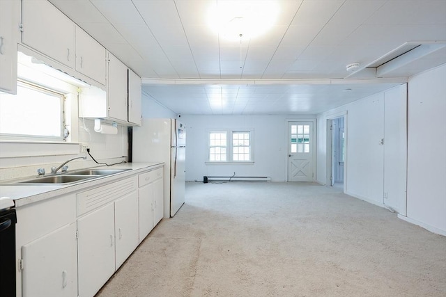 kitchen featuring white cabinetry, sink, white refrigerator, a baseboard heating unit, and light colored carpet