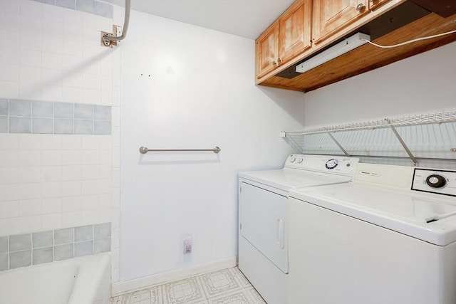 clothes washing area featuring separate washer and dryer and cabinets