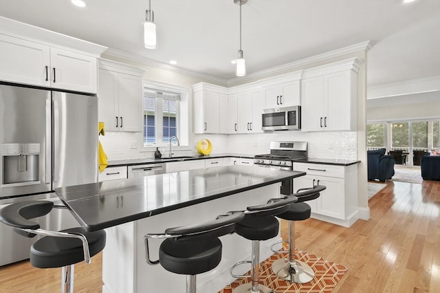 kitchen featuring appliances with stainless steel finishes, dark countertops, crown molding, and a sink