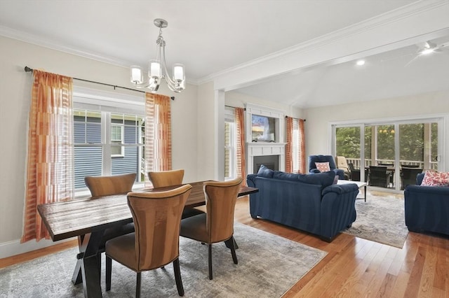 dining space with baseboards, ornamental molding, wood finished floors, a fireplace, and a notable chandelier