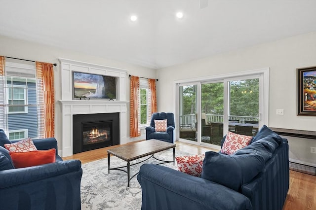 living area featuring light wood-style floors, a glass covered fireplace, baseboards, and recessed lighting