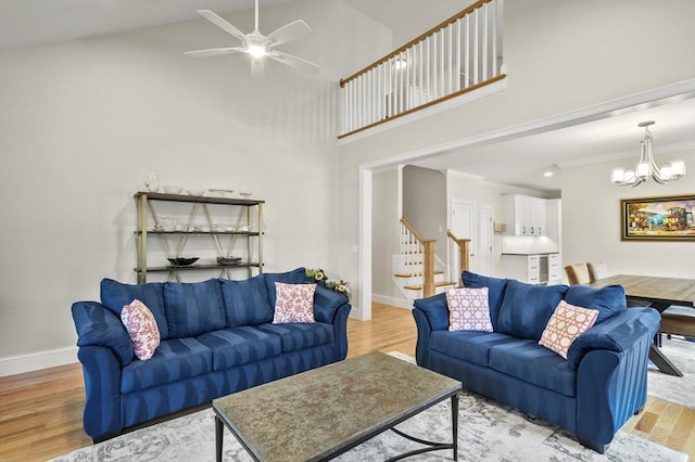 living room featuring light wood-style floors, crown molding, stairway, and baseboards