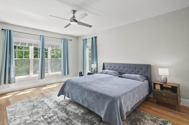 bedroom with a ceiling fan, baseboards, and wood finished floors