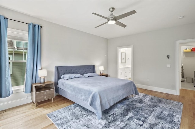 bedroom featuring a ceiling fan, ensuite bathroom, baseboards, and wood finished floors