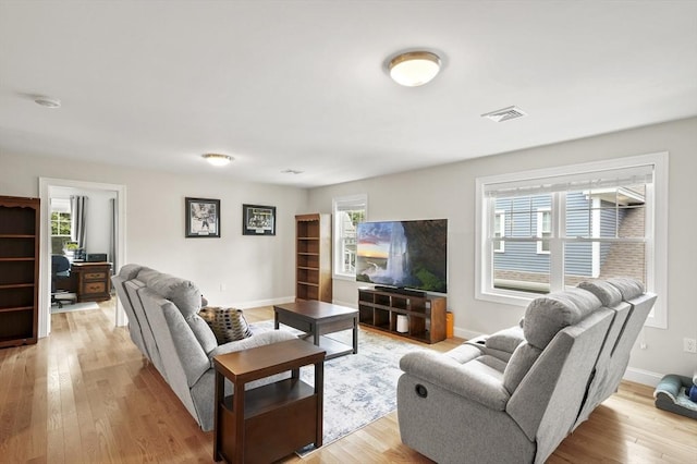 living room featuring light wood-type flooring, baseboards, and visible vents