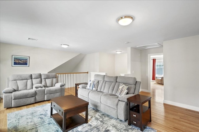 living area featuring light wood-style floors, attic access, visible vents, and baseboards