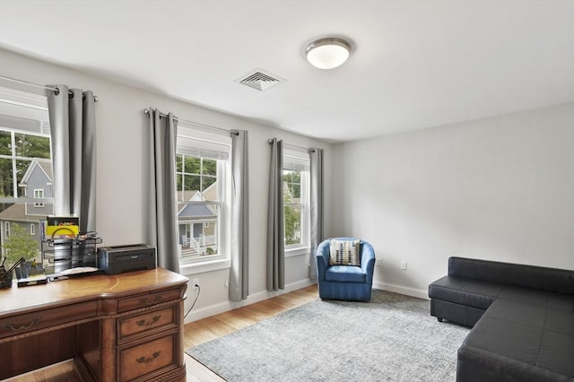 home office with light wood-type flooring, visible vents, and baseboards