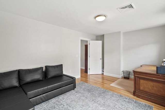 living area with light wood-type flooring, visible vents, and baseboards