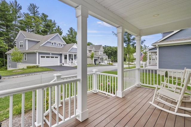 deck featuring a garage, aphalt driveway, a residential view, and a porch