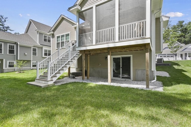 rear view of property featuring a sunroom, stairway, and a yard