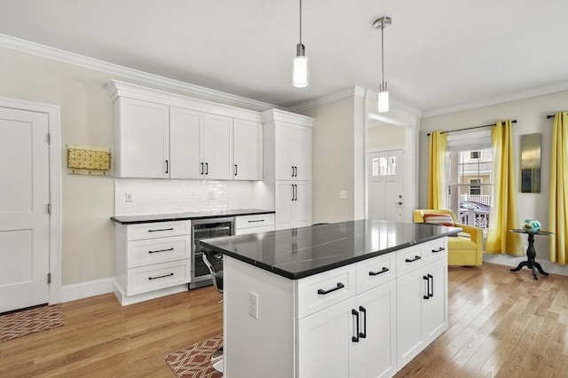 kitchen with ornamental molding, wine cooler, and light wood-style floors