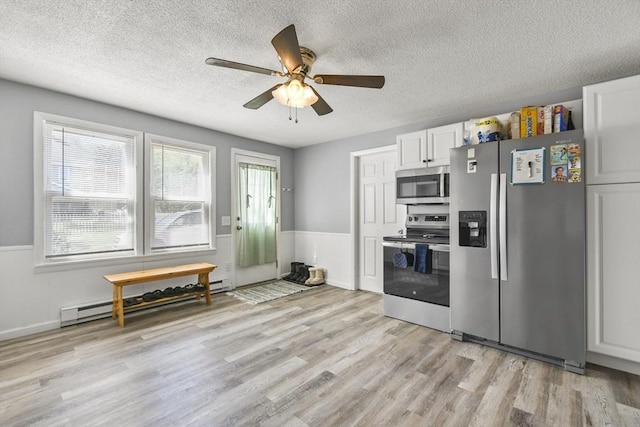 11 Broad St Unit 11, Hardwick, MA 01005 - kitchen featuring stainless steel appliances, baseboard heating, a textured ceiling, light wood-style flooring, and a wainscoted wall