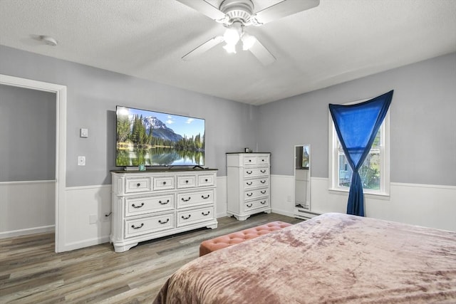 11 Broad St Unit 11, Hardwick, MA 01005 - bedroom with wood finished floors, a wainscoted wall, a baseboard heating unit, ceiling fan, and a textured ceiling