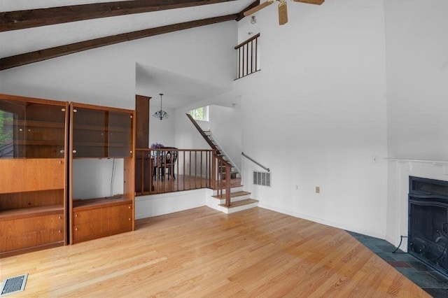 401 Colonial Dr Unit 35, Ipswich, MA 01938 - unfurnished living room featuring wood finished floors, stairs, beamed ceiling, a fireplace with flush hearth, and high vaulted ceiling