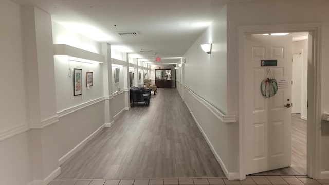 hallway with visible vents, baseboards, and wood finished floors