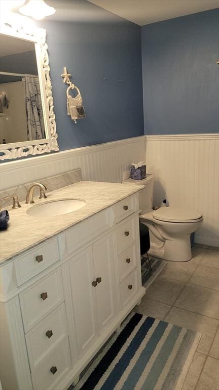 bathroom with tile patterned flooring, vanity, toilet, and walk in shower