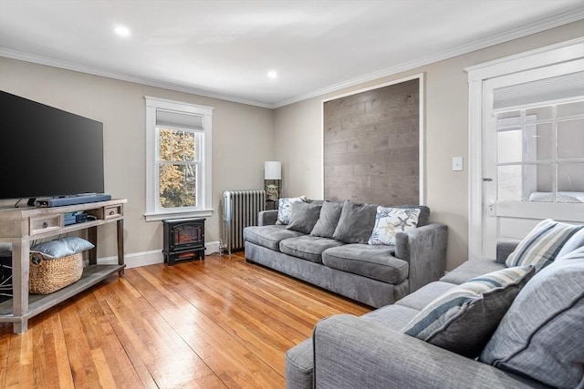 living room with ornamental molding, radiator heating unit, wood-type flooring, and a wood stove