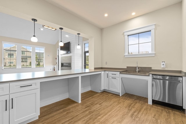 kitchen featuring stainless steel dishwasher, sink, light hardwood / wood-style flooring, a fireplace, and white cabinetry