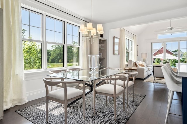 dining area featuring lofted ceiling, a wealth of natural light, ceiling fan with notable chandelier, and dark hardwood / wood-style floors