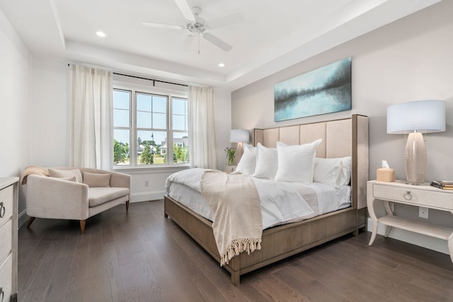 bedroom with a tray ceiling, ceiling fan, and dark hardwood / wood-style flooring