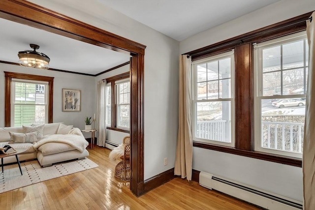 interior space featuring baseboards, crown molding, a baseboard radiator, and light wood-style floors