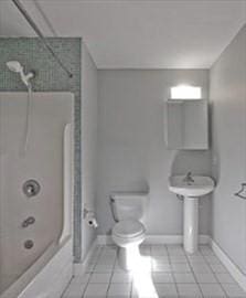 bathroom featuring tile patterned flooring, tiled shower / bath, and toilet