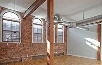 interior space with hardwood / wood-style flooring and brick wall