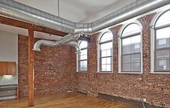 interior space featuring hardwood / wood-style floors and brick wall