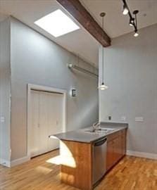 kitchen featuring hanging light fixtures, light hardwood / wood-style flooring, stainless steel dishwasher, track lighting, and beamed ceiling