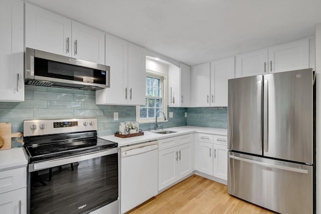 kitchen featuring appliances with stainless steel finishes, a sink, light countertops, and white cabinetry
