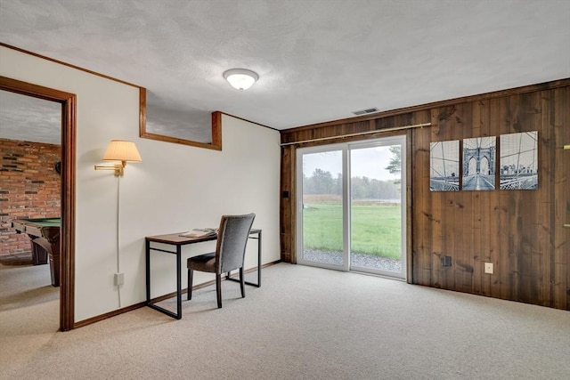 office featuring light carpet, wood walls, baseboards, a textured ceiling, and crown molding