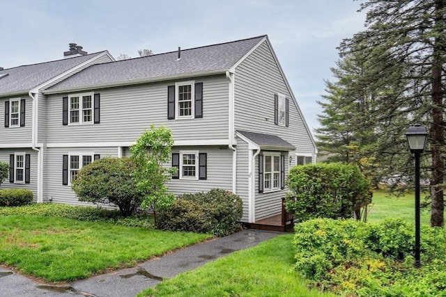 view of property exterior featuring a lawn and roof with shingles