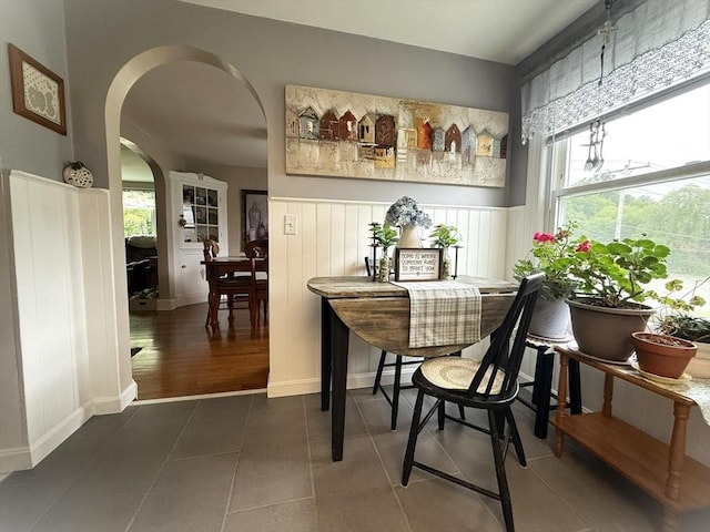 4 Perryville Rd, Webster, MA 01570 - dining space featuring arched walkways, a wainscoted wall, dark tile patterned floors, and baseboards