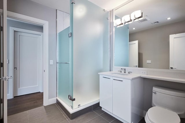 bathroom with tile patterned floors, vanity, toilet, and a shower with door