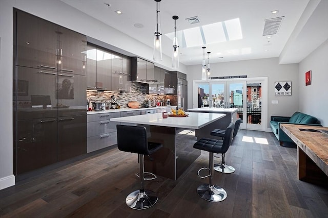 kitchen with hanging light fixtures, gray cabinets, dark hardwood / wood-style floors, and a kitchen bar