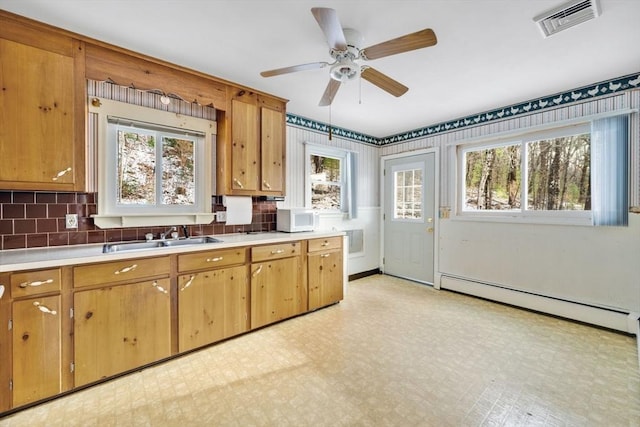 kitchen featuring ceiling fan, backsplash, baseboard heating, and sink