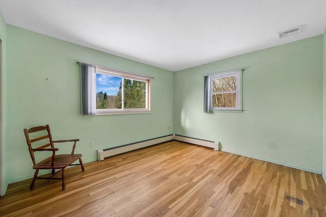 spare room featuring plenty of natural light, light hardwood / wood-style floors, and a baseboard heating unit